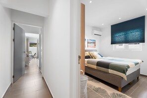 A modern bedroom with a bed, a large window, and a view of the outdoors. - Modern Three Bedroom Villa in Noord (Boegoeroei)