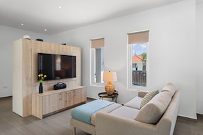 A modern living room with a flat-screen TV, wooden entertainment unit, a sofa, and a lamp. - Modern Three Bedroom Villa in Noord (Boegoeroei)