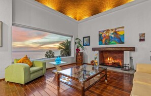 A living room with a large window, a fireplace, and a painting. - New Listing (Cabo San Lucas)