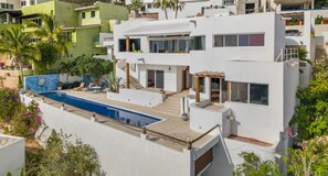 A modern two-story house with a swimming pool, outdoor seating, and a balcony. - New Listing (Cabo San Lucas)