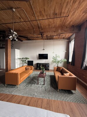 Ein modernes Wohnzimmer mit Holzboden, zwei Sofas, einem Couchtisch und einem Flachbildfernseher.