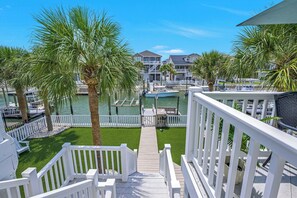 A waterfront property with a wooden deck, palm trees, and a marina. - OIB Waterfront Retreat w/ Dock & Golf Cart 5BR (Ocean Isle Beach)