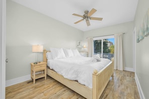 A bedroom with a bed, a nightstand, a ceiling fan, and a window with curtains. - OIB Waterfront Retreat w/ Dock & Golf Cart 5BR (Ocean Isle Beach)