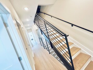 Un intérieur moderne avec un escalier en bois, des rampes en métal et une porte blanche.