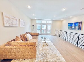 A modern living room with a sofa, a coffee table, and artwork on the walls. - Luxurious 3BR @ H St Corridor Free Cancellation (Washington)