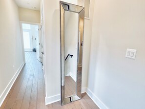 A hallway with a large mirror, a door, and a light switch on the wall. - Luxurious 3BR @ H St Corridor Free Cancellation (Washington)