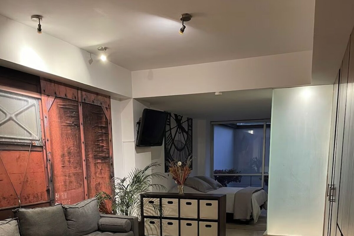 Ein modernes Wohnzimmer mit einer Eckcouch, einem Glastisch und einer dekorativen Wandverkleidung.
