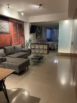 A modern living room with a sectional sofa, a glass coffee table, and a decorative wall unit. - Depto 203 (Ciudad de México)