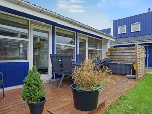 A patio area with a wooden deck, two potted plants, and a seating arrangement with chairs and a table. - "Kielo" - 700m from the sea by Interhome (Væggerløse)