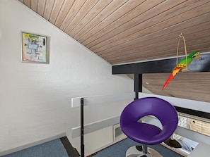 A room with a sloped ceiling, a purple chair, a wooden desk, and a hanging parrot. - "Kielo" - 700m from the sea by Interhome (Væggerløse)