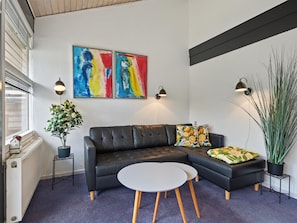 A modern living room with a black leather sofa, a round white table, and two abstract paintings. - "Kielo" - 700m from the sea by Interhome (Væggerløse)