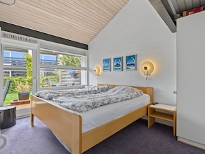 A modern bedroom with a large bed, two wall-mounted reading lights, and a view of greenery outside. - "Kielo" - 700m from the sea by Interhome (Væggerløse)