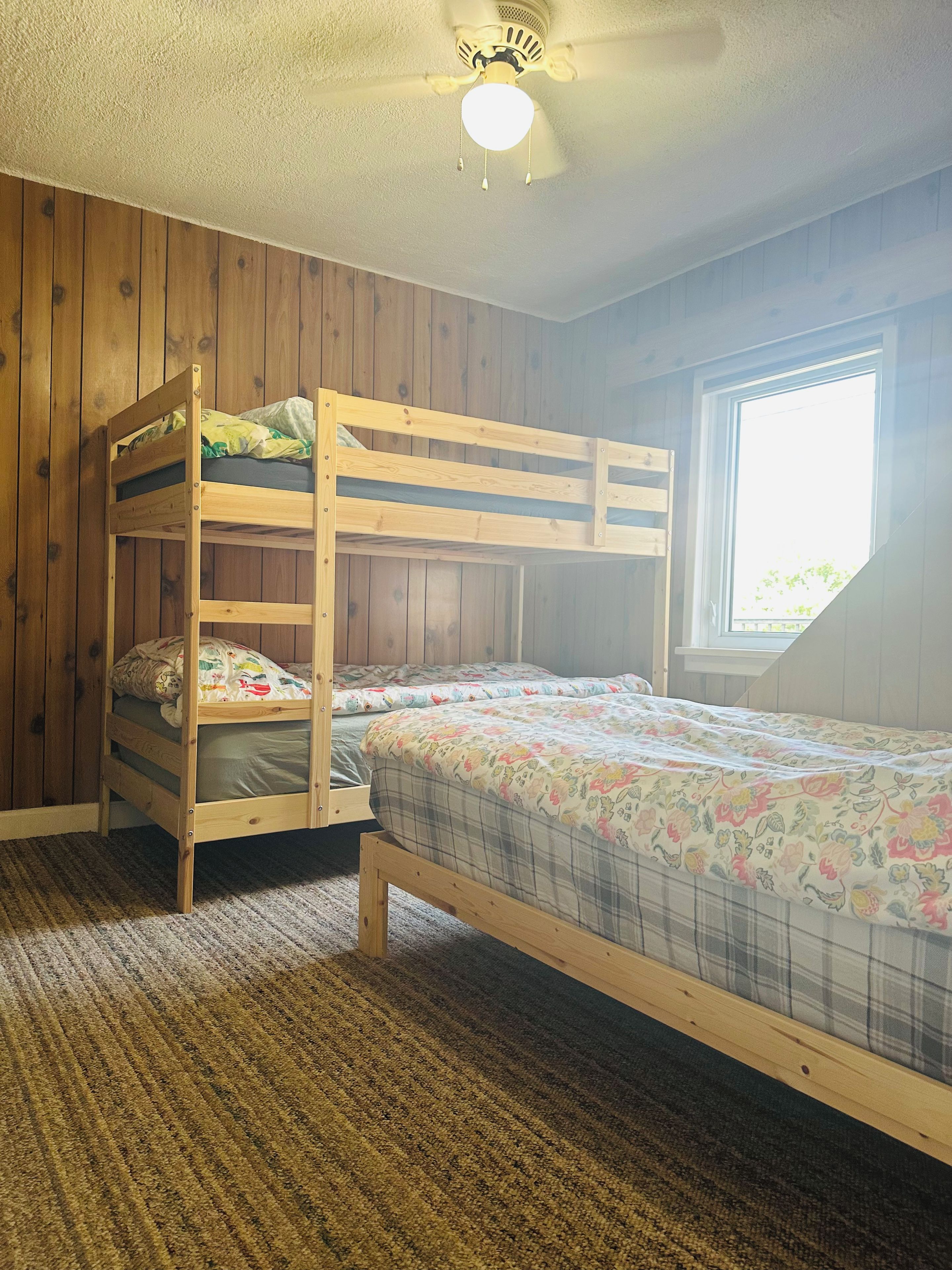 A bunk bed room with a window and a ceiling fan.
