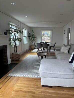 A spacious living room with a fireplace, a dining area with a table and chairs, and a large window providing natural light. - 4-bedroom Eastside single home with cool AC for relaxing stay (Providence)