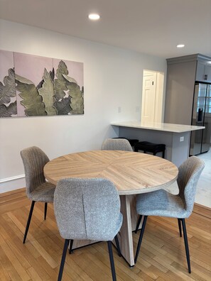 A dining area with a round wooden table and four grey upholstered chairs. - 4-bedroom Eastside single home with cool AC for relaxing stay (Providence)