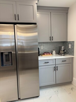 A kitchen with stainless steel appliances, grey cabinets, a tiled backsplash, and a coffee maker on the countertop. - 4-bedroom Eastside single home with cool AC for relaxing stay (Providence)