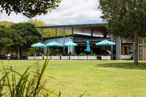 An outdoor seating area with umbrellas, a covered structure, and a building in the background. - Ocean Breeze at Palm Beach (Palm Beach)