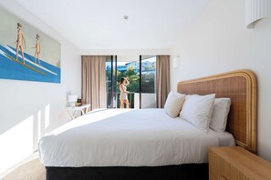 A hotel room with a large bed, a painting on the wall, a desk with a lamp, and a view of the outside. - The Rocks 11H Currumbin Escape with Ocean Views (Currumbin)