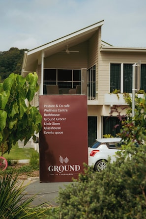 A signboard listing amenities including a café, wellness centre, and events space at a property named Ground at Currumbin. - Whispering Creek - Luxury Off Grid Escape (Currumbin Valley)