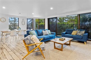 A modern living room with two blue sofas, a wooden coffee table, and a patterned armchair. - The Rocks Resort GA  Currumbin Beach apartment (Currumbin)