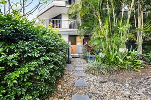 A pathway leading to a modern building with a balcony, surrounded by lush greenery and tropical plants. - The Rocks Resort GA  Currumbin Beach apartment (Currumbin)
