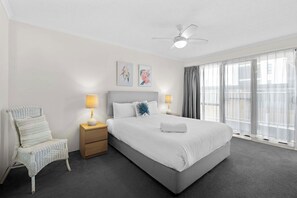 A hotel room with a bed, two bedside lamps, a chair, a ceiling fan, and a window with curtains. - Surfside 8 with direct beach access. (Palm Beach)