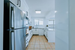 A modern kitchen with white cabinetry, a stainless steel refrigerator, and a dishwasher. - Surfside 13 near Palm Beach (Palm Beach)