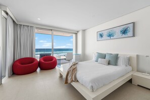 A modern bedroom with a large bed, a view of the ocean, and a balcony with red chairs. - Joy on Jefferson Stunning Palm Beach Escape (Palm Beach)