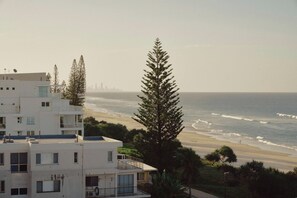 A coastal residential area with modern buildings, a beach, and a distant city skyline. - Golden Era - Tugun Beachfront (Tugun)
