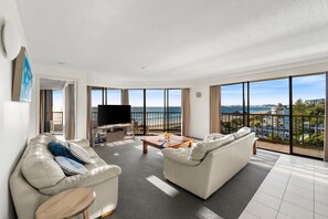 A spacious living room with a large TV, comfortable seating, and a view of the ocean. - The Rocks Resort 8J on Currumbin Beach (Currumbin)