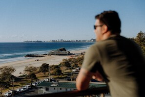 A coastal view with a building near the beach, a parking area, and a clear sky. - The Rocks Resort 8J on Currumbin Beach (Currumbin)