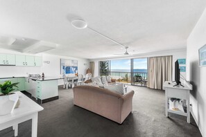 A modern living room with a sofa, dining table, and kitchen area. - The Rocks Resort 5D with Ocean View (Currumbin)