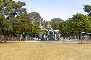 A park with playground equipment, a covered seating area, and trees. - Coastal House Palm Beach Retreat (Palm Beach)
