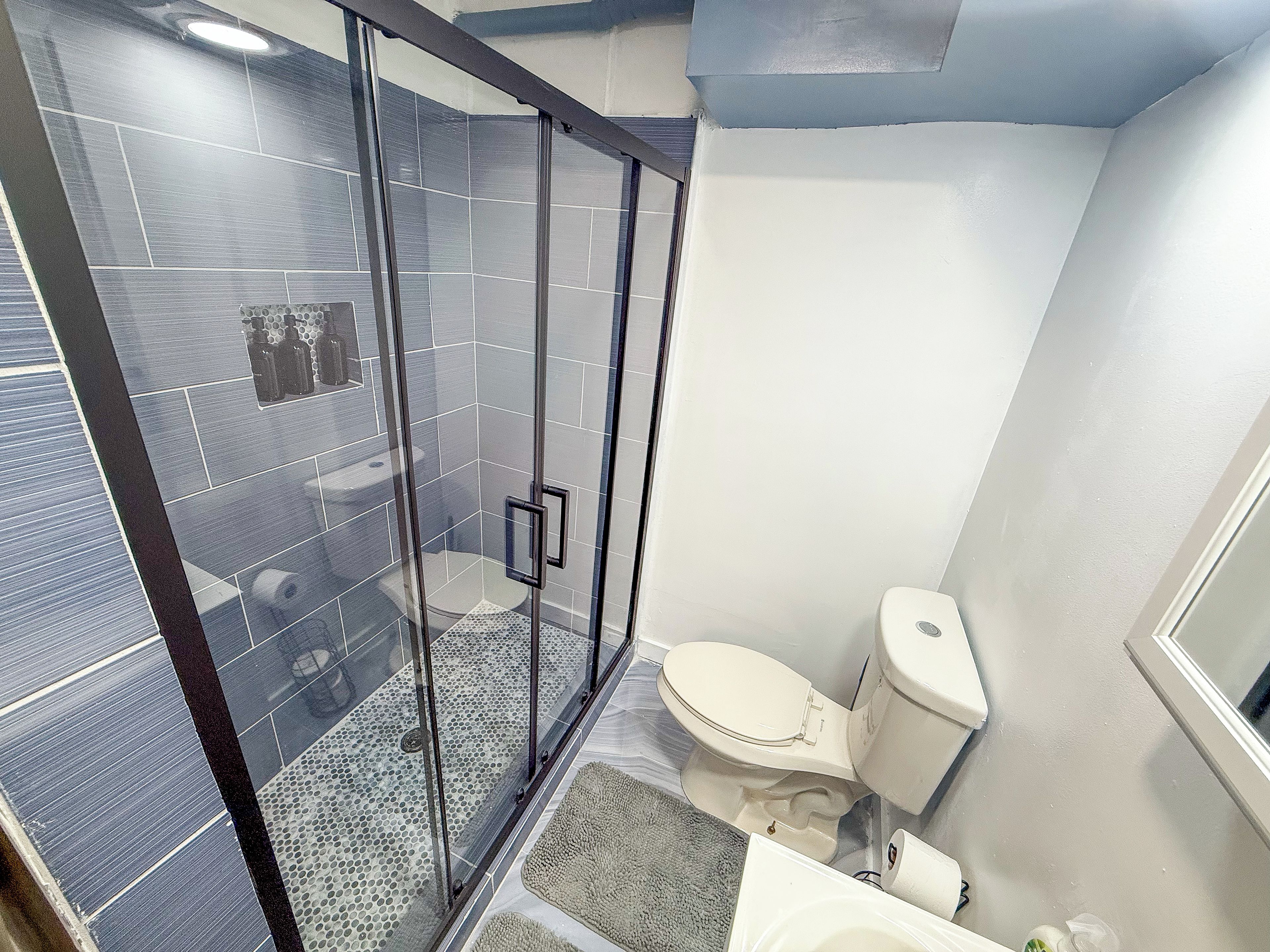 A bathroom with a glass-enclosed shower, a toilet, and a sink.
