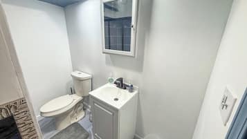 A small bathroom with a toilet, sink, and mirror.