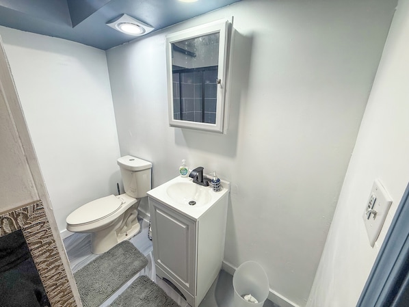 A small bathroom with a toilet, sink, and mirror.