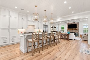 A modern kitchen with white cabinetry, a central island, and bar stools. - Your Island Escape | Heated Pool, Game Room & Private Yard for the Pups! (Saint Simons Island)