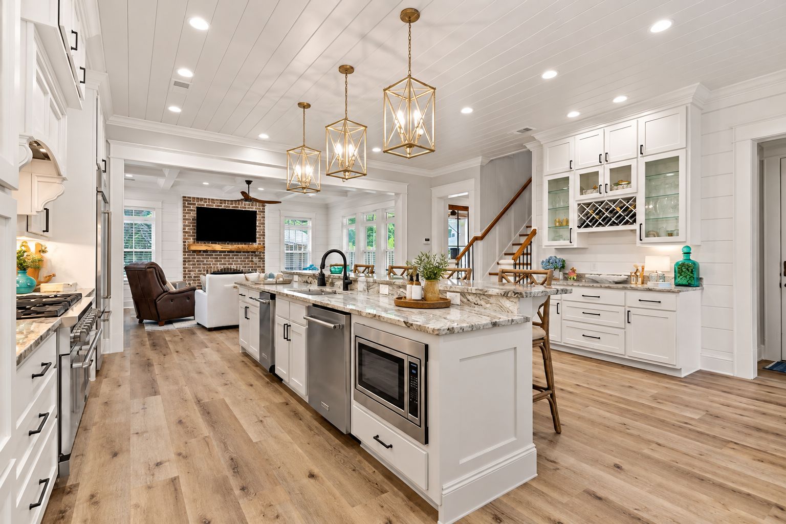 A spacious kitchen with white cabinetry, a central island, and a brick wall.