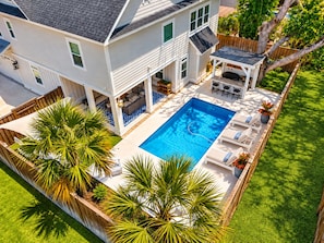 Une maison à deux étages avec une piscine, du mobilier d’extérieur et une terrasse en bois.