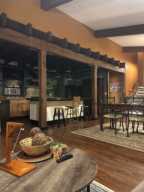 A spacious dining area with a wooden table and chairs, a kitchen in the background, and a staircase leading to an upper level. - Daisy Hill Retreat: 4BR/3BA Mins to downtown Asheville and Blue Ridge Parkway! (Swannanoa)
