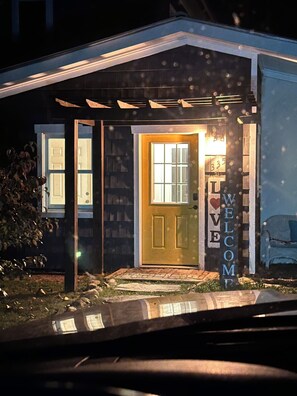 A house with a dark exterior, a yellow front door, and a 'WELCOME' sign. - Daisy Hill Retreat: 4BR/3BA Mins to downtown Asheville and Blue Ridge Parkway! (Swannanoa)