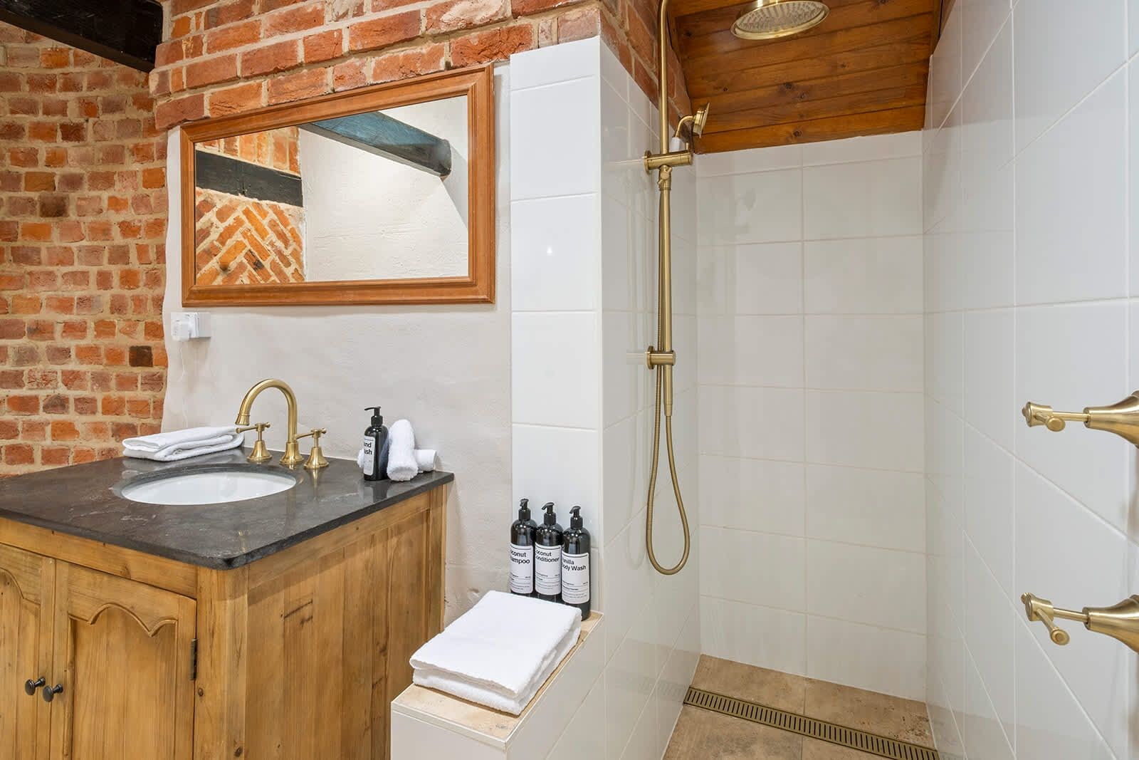 A bathroom with a wooden vanity, a sink, and a shower with a handheld showerhead.