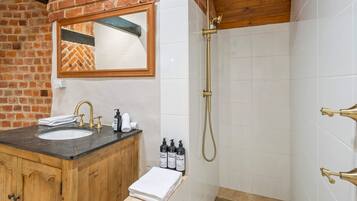 A bathroom with a wooden vanity, a sink, and a shower with a handheld showerhead.