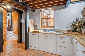 A kitchen with white cabinets, a wooden countertop, and a window with a view of the outside. - Sheiling 1888  A Honey Home (Dubbo)