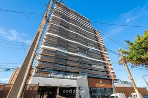 A multi-story hotel with a modern design, featuring balconies on each floor, a beach club sign, and a storefront with a sign that reads 'seozone'. - Apt. w/ Beach View in Condo. w/ Pool Nri0401 (Salvador)
