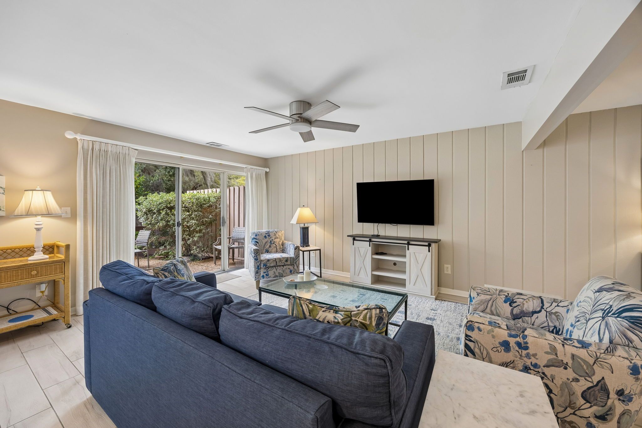 A living room with a sofa, a coffee table, a television, and a ceiling fan.