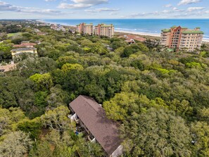 Zona costera con varios edificios, vegetación densa y una playa al fondo.