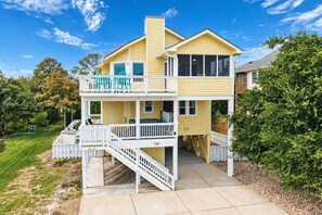 A two-story house with a balcony and a covered porch. - Beach Please OBX | 1,550 ft to the beach | Private Pool, Hot Tub, and Dog Friendly (Corolla)