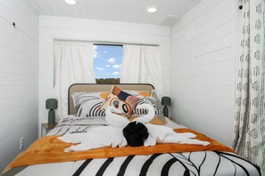 A neatly made bed with striped bedding, a decorative pillow, and a swan-shaped towel arrangement. - 1BR Fredericksburg retreat with hot tub, fire pit, grill (Fredericksburg)