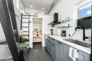 A modern kitchen with a built-in oven, a coffee maker, and a window with a view. - 1BR Fredericksburg retreat with hot tub, fire pit, grill (Fredericksburg)